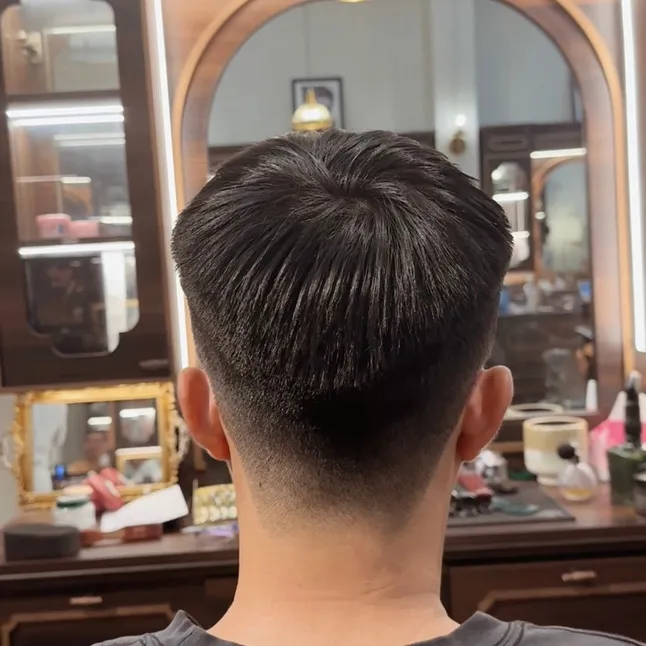 Một người đàn ông đang thoa sản phẩm dưỡng tóc hoặc tạo kiểu lên mái tóc cứng