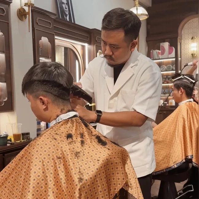 Một người đàn ông trẻ đang vuốt tóc của mình sau khi tạo kiểu bằng sản phẩm dưỡng