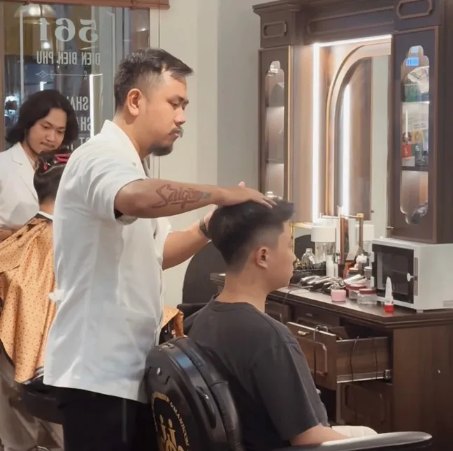 Một người đàn ông đang được tư vấn kiểu tóc trong salon, tập trung vào cách tạo kiểu cho tóc rễ tre