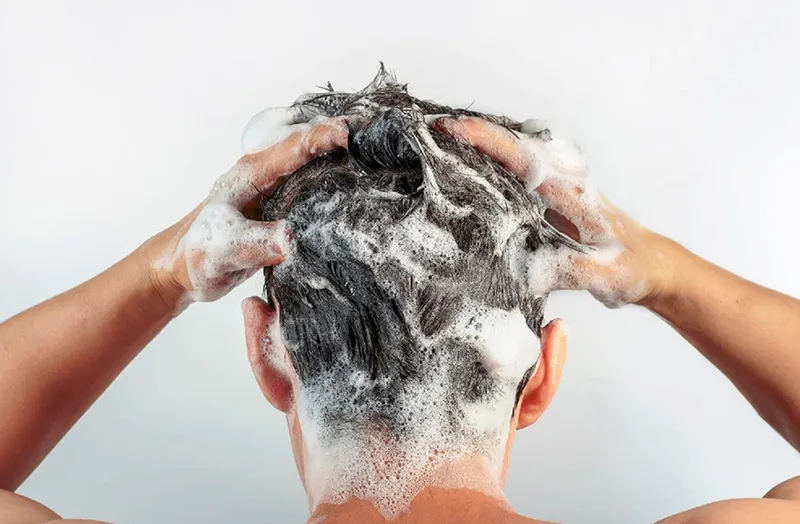 Người đang gội đầu nhẹ nhàng, minh họa cách chữa tóc khô bằng việc áp dụng tần suất và kỹ thuật gội phù hợp