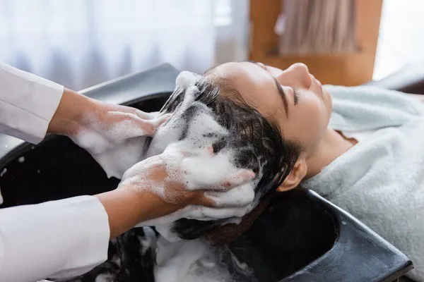 Kỹ thuật viên đang gội đầu cho khách hàng trong một salon tóc chuyên nghiệp
