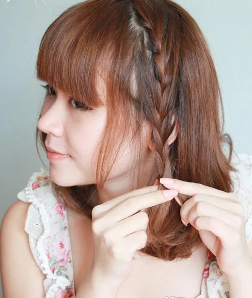 Cô gái có tóc ngắn tết hai lọn tóc nhỏ ở lớp ngoài cùng, buông xõa tóc còn lại