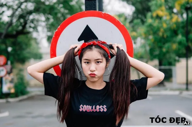 Một cô gái khác với mái tóc buộc hai bên cao, lọn tóc có độ xoăn nhẹ và dùng phụ kiện tóc nổi bật