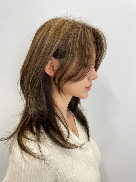 Hình ảnh một kiểu tóc layer dài với mái bay, làm tôn lên vẻ duyên dáng và phù hợp với khuôn mặt tròn.