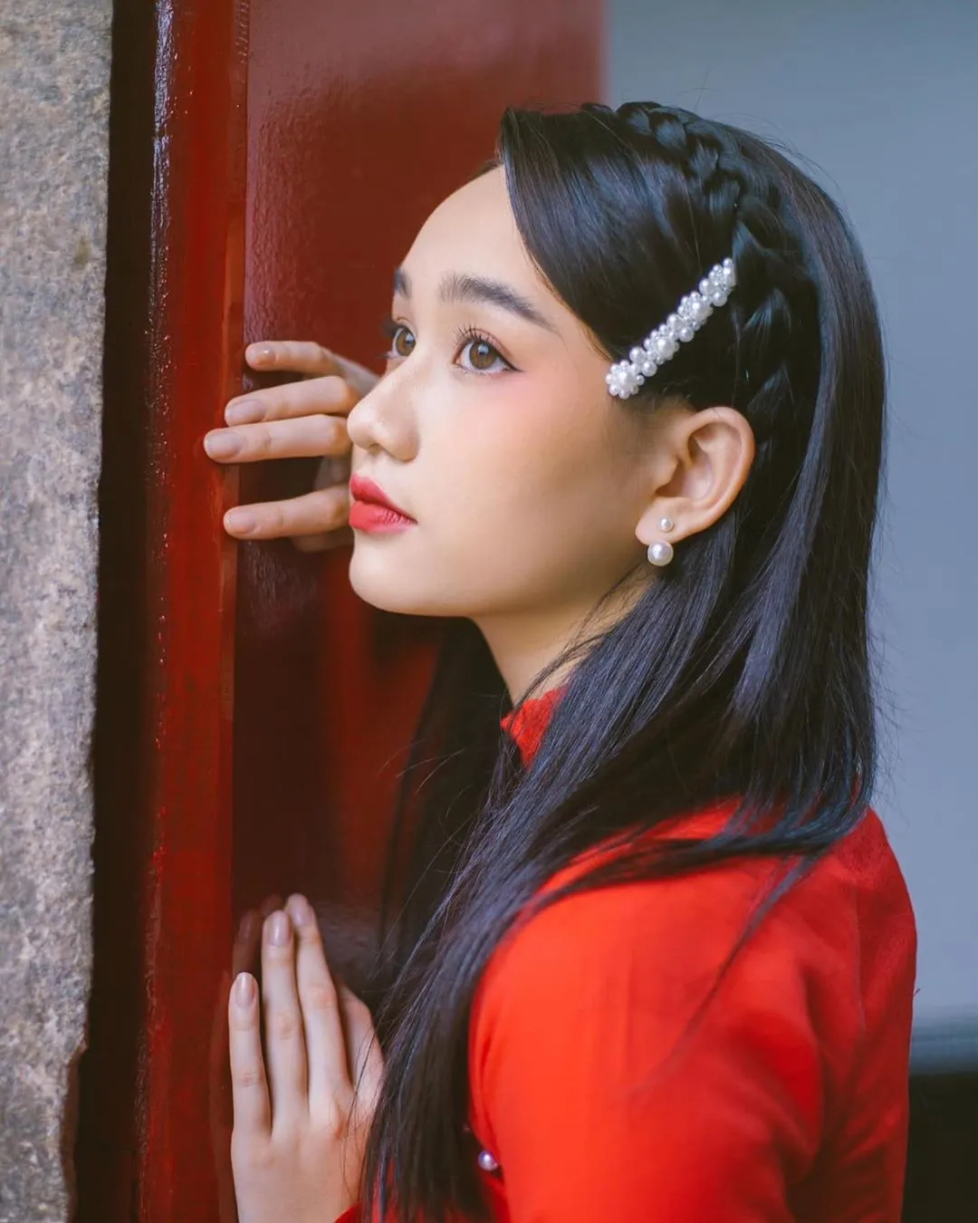 Một phụ nữ trong trang phục áo dài truyền thống, với kiểu tóc thẳng dài hoặc uốn sóng nước nhẹ nhàng, thích hợp cho dịp Tết