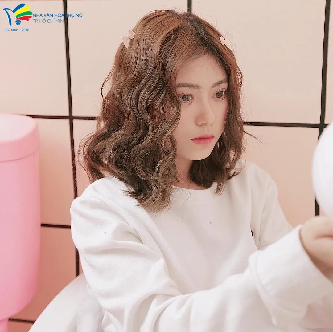 Hình ảnh người phụ nữ đang sử dụng máy sấy tóc ở chế độ nhiệt thấp, minh họa việc không lạm dụng nhiệt khi làm tóc xoăn đơn giản