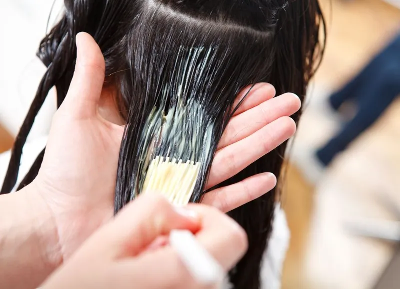 Hình ảnh minh họa quá trình nâng tone tóc đang diễn ra, với thuốc được thoa đều trên tóc, trong quá trình thực hiện cách nâng tone tóc