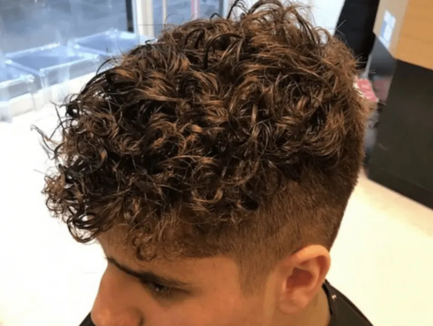 Nam giới đang sử dụng máy sấy tóc với đầu khuếch tán để định hình và làm khô tóc uốn xoăn