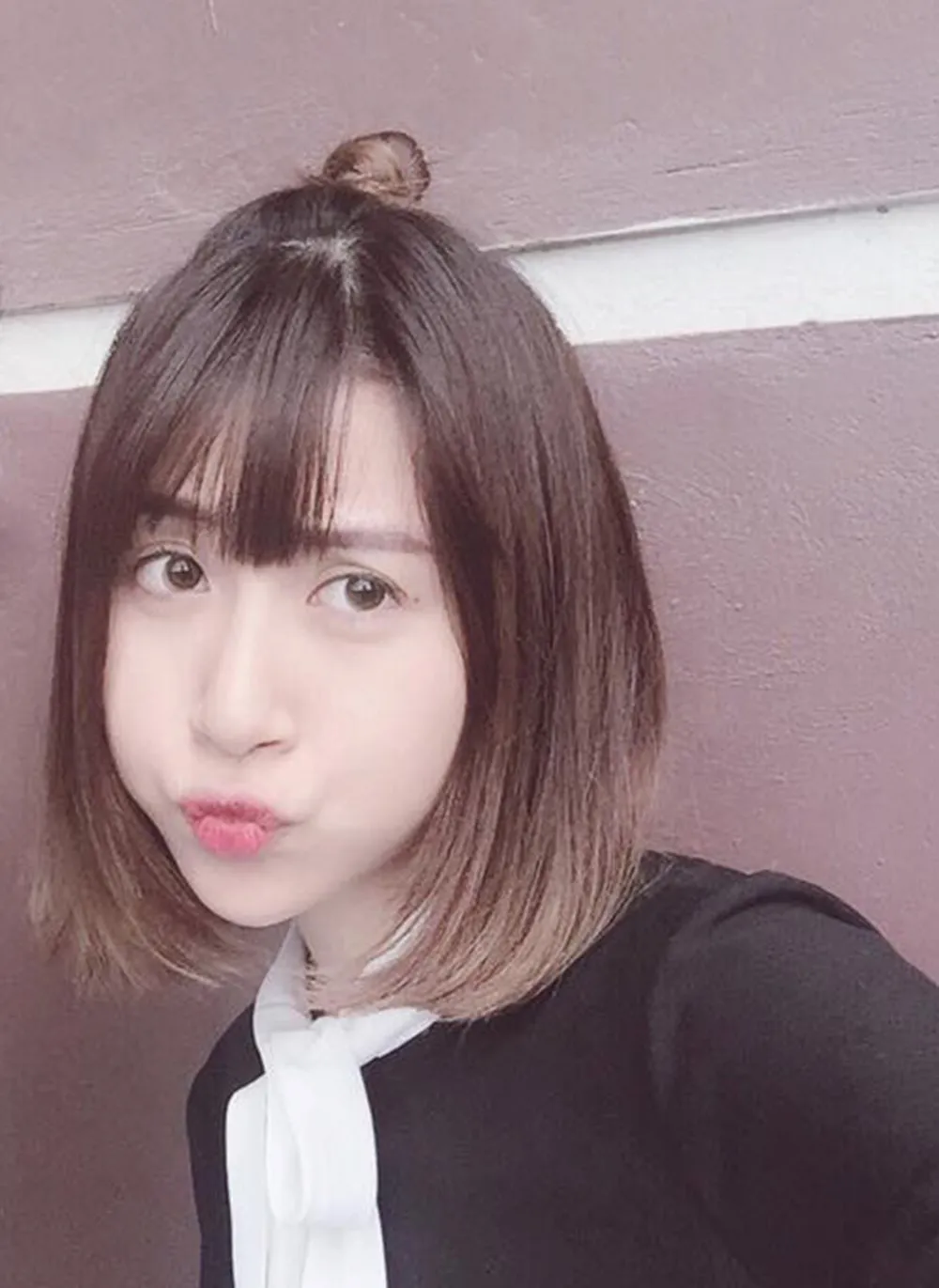 Tóc ngắn được tạo kiểu búi rối nửa đầu, với những lọn tóc xõa tự nhiên quanh khuôn mặt