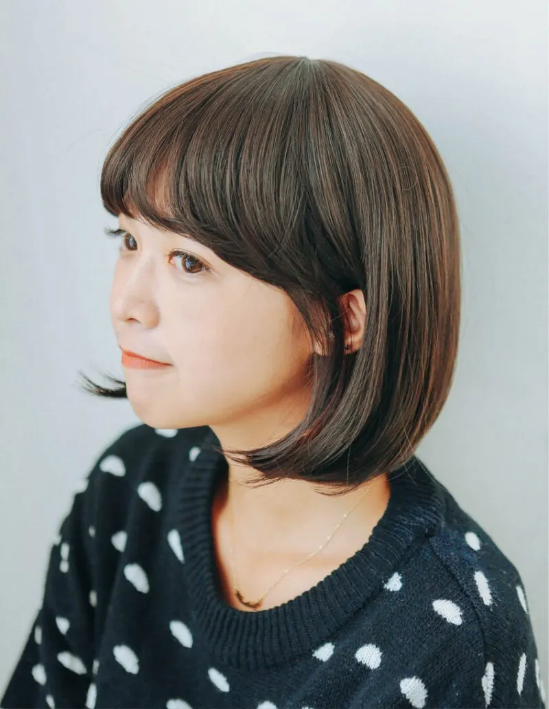 Một cô gái đeo tóc giả mái thưa với tông màu tóc nâu ấm áp, tạo nên vẻ ngoài dịu dàng và thanh lịch