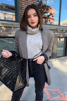 Cô gái tóc ngắn mặc áo cổ lọ màu ghi nhạt phối cùng quần skinny jeans đen, thêm áo khoác và túi xách để tạo vẻ ngoài sành điệu