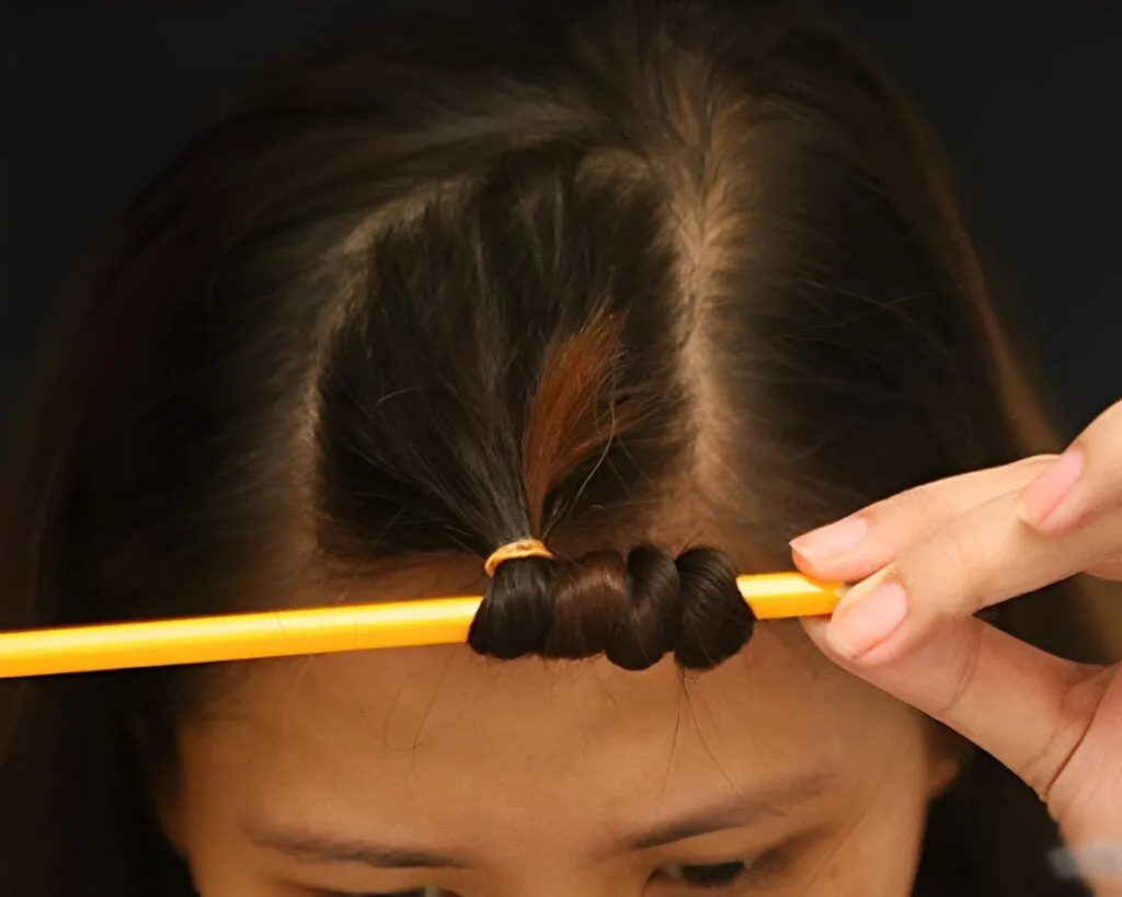 Phụ nữ đang cuốn tóc quanh lô vải để tự làm tóc xoăn tại nhà không dùng nhiệt