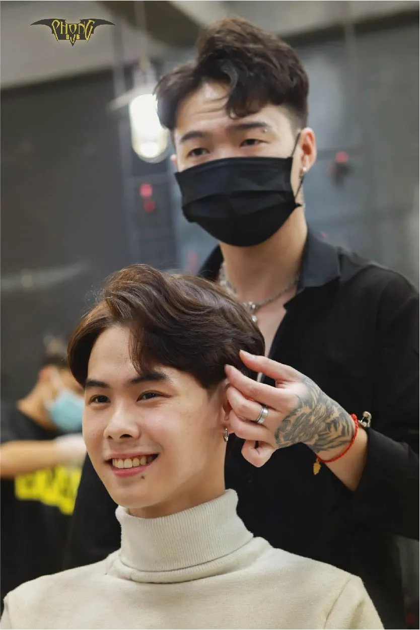 Hình ảnh một người đang sấy tóc bằng máy sấy có gắn lược tán khí (diffuser), thực hiện theo hướng dẫn của thợ làm tóc để giữ nếp xoăn